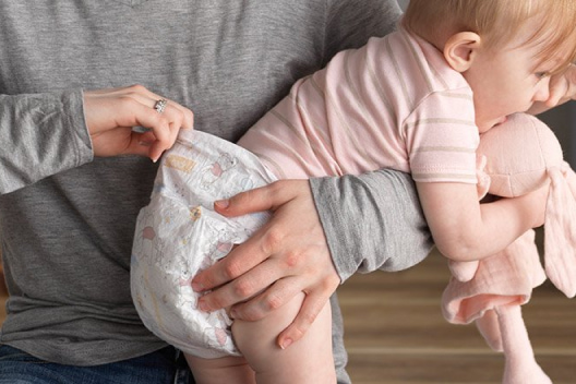 A parent holds their baby wearing a hypoallergenic and breathable Huggies Little Snugglers Diaper